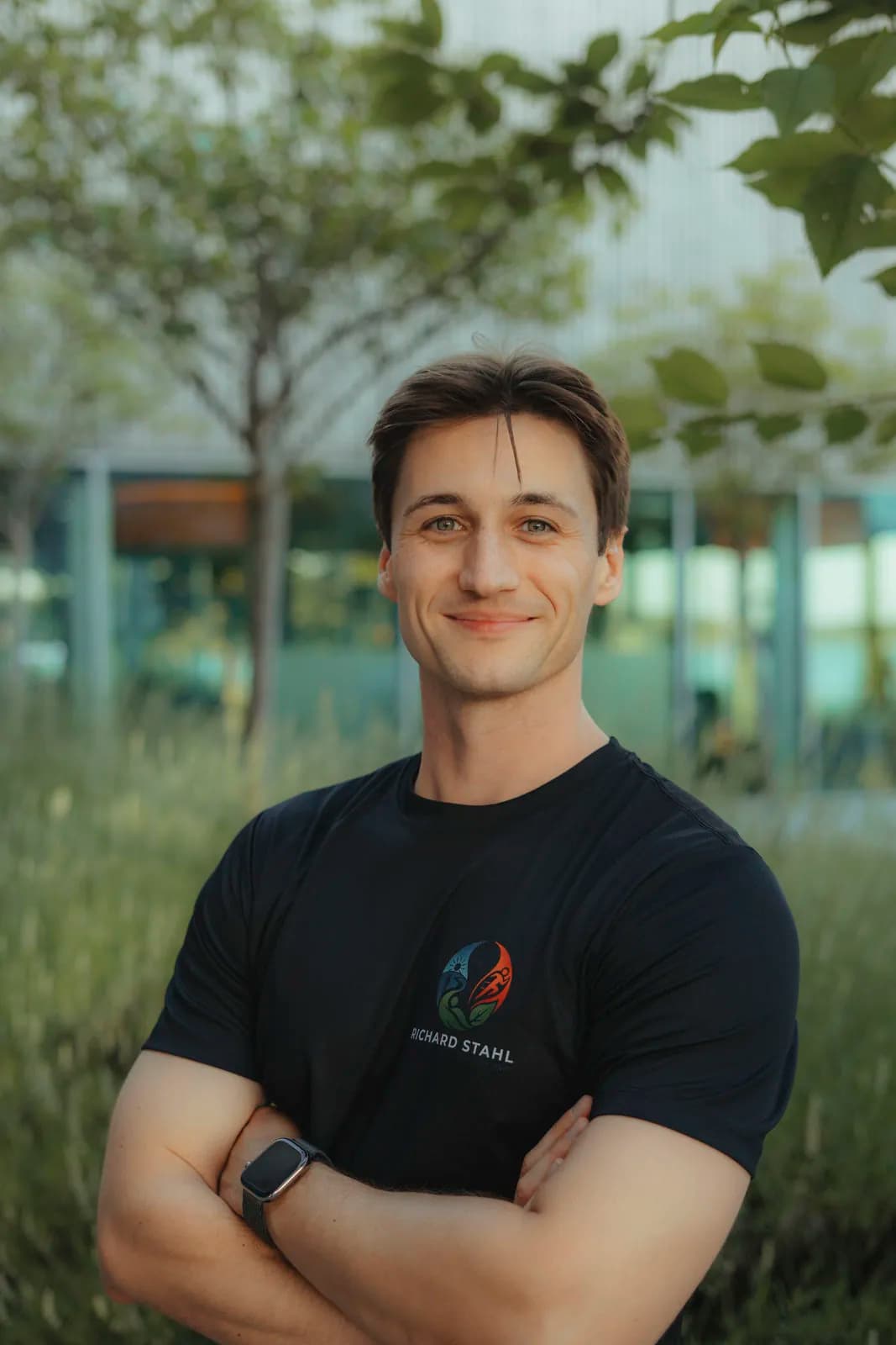 Richard Stahl, Personal Trainer und Physiotherapeut, im Grünen vor einer modernen Glasfassade