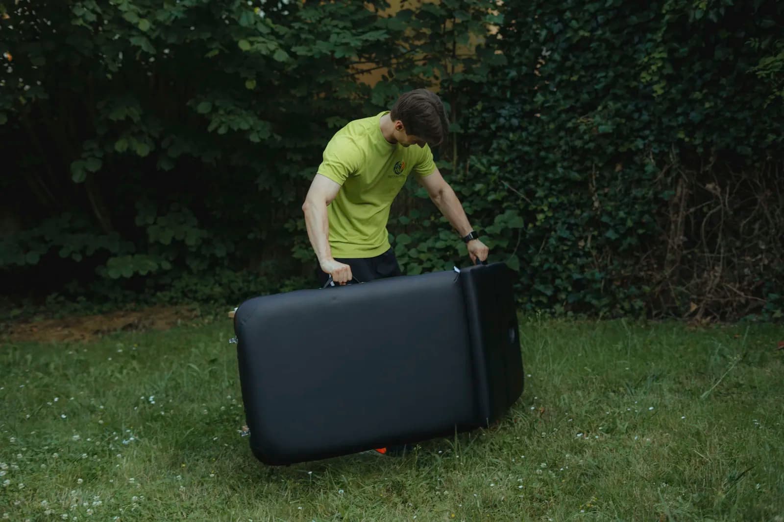 Richard Stahl trägt die mobile Behandlungsliege im Garten zum Hausbesuch