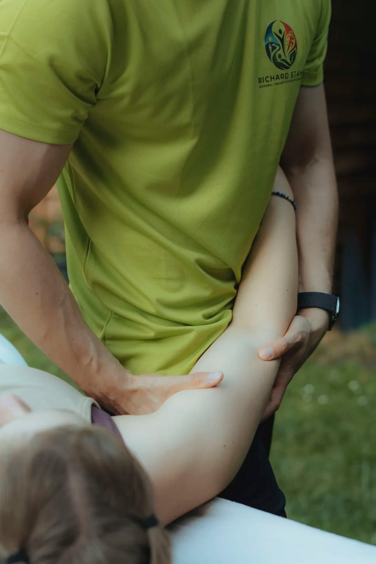 Physiotherapeut führt eine geführte Übung am Bein einer liegenden Person aus