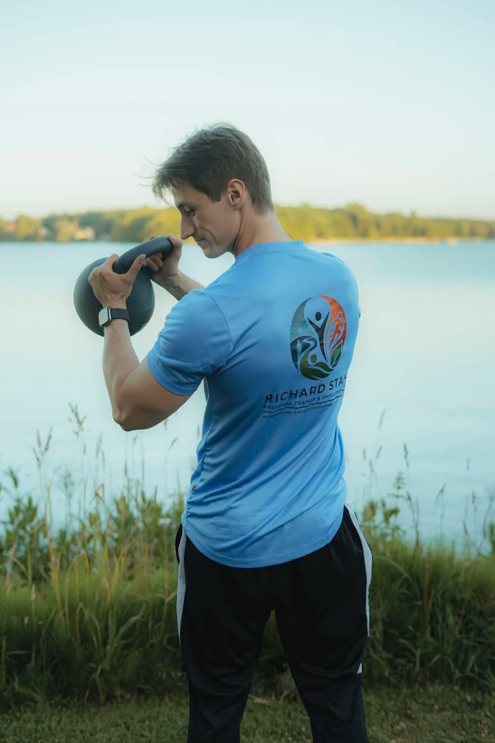 Richard Stahl trainiert konzentriert mit der Kettlebell am Seeufer
